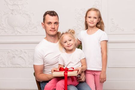 Happy father and his daughters holding gift box and smile. Fathers day. Selective focusの写真素材
