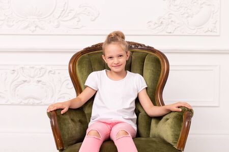 Little blond smiling girl sits in green armchairの写真素材