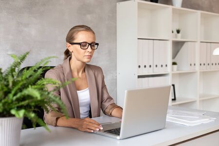 Blond woman in glasses working with lapatop. Office workerの写真素材