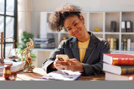 Portrait of black young business woman in afro hair answering phone calls at desk in office and...