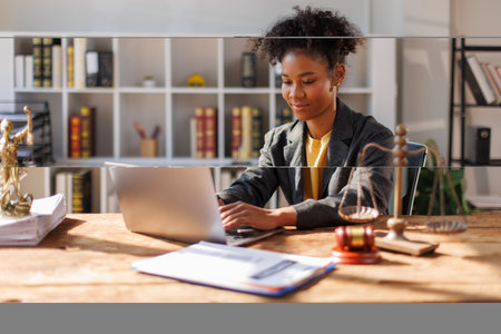 A woman in afro hair paralegal immersed in work at a law office, surrounded by paperwork and legal...