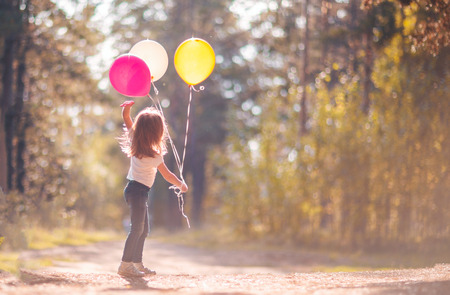 Little girl playing with balloons outdoorsの写真素材