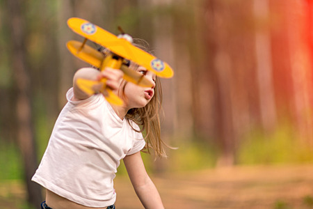 Little girl playing with toy airplane outdoors. Dreams of travelingの写真素材