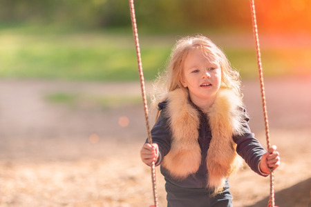 Little girl on swing. Kid having fun on a playground outdoorsの写真素材