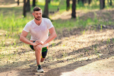Athletic man runner stretching legs before run. Healthy, fitness, wellness lifestyle. Sport, cardio, workout conceptの写真素材
