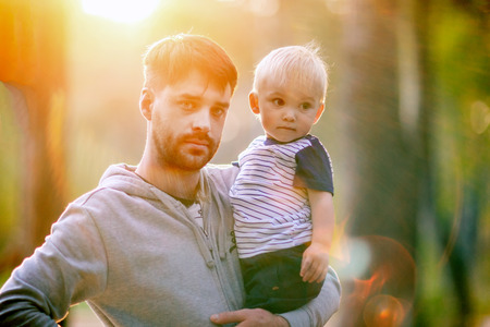 Young father holds his son. Man with his little baby outdoors.