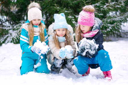 Three cute girl kids making snowballs together in winter forest.の写真素材