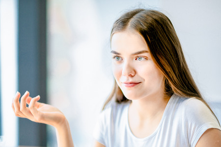 A teenage blue-eyed girl looking at someone with a smile.の写真素材