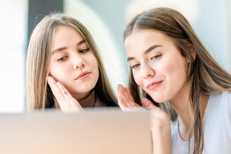 Two students sitting at lesson looking into monitor of laptop.の写真素材