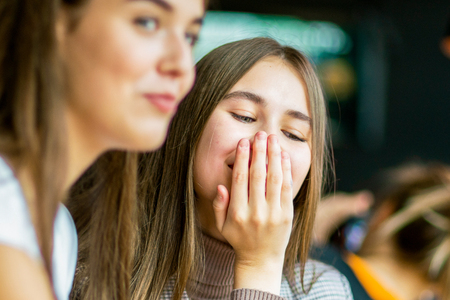 Two teenage girls have cheerful conversation in cafe.の写真素材