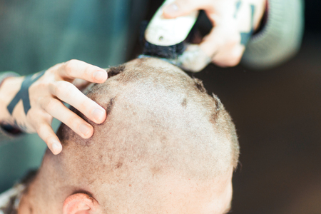 Male hands shaving head of a customer in barbershop.の写真素材