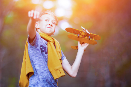 Handsome boy playing with yellow toy airplane outdoors. Dreams of travelingの写真素材