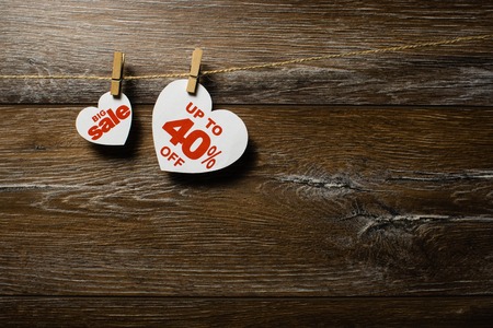 Big sale on hearts hanging on rope with clothespins over the wooden background. Forty percent discount promotion written on white heartの写真素材