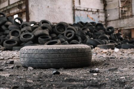 old car tire lying on the ground of an abandoned factory compared to other tires.の写真素材