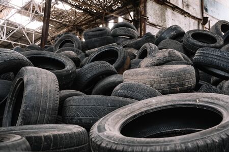 A pile of old rotten rubber tires on the ruined building background.