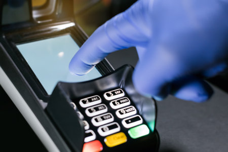 gloved hand using POS terminal machineの写真素材