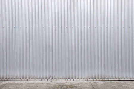 ribbed aluminum wall side of factory wall with pavementの写真素材