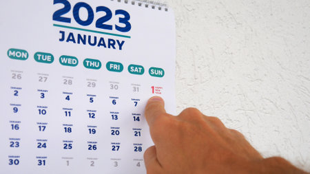 A man points a finger at New Year's date on the wall calendar January page 2023