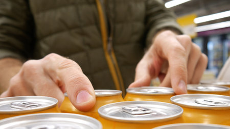 Close-up of many orange cans of beer and a male buyer's hands taking a coupleの写真素材