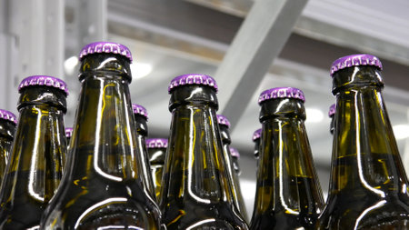 Close-up of many glass bottles of beer or beverage with violet capsの写真素材