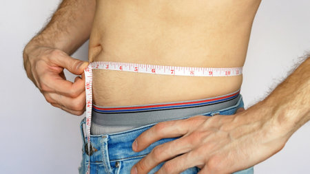 A young man in blue jeans measures his waistの写真素材
