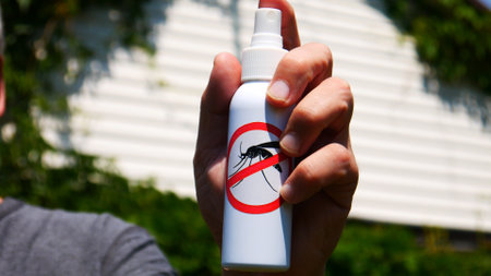Close-up of the mosquito spray in the hand of a man against a summer house backgroundの写真素材