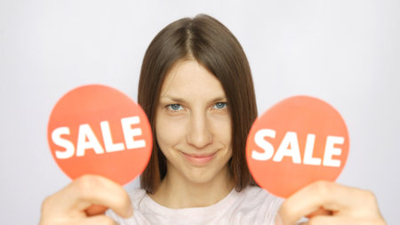 Close up of a lovely girl showing two red round signs with the word SALE