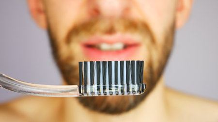 A smiling bearded man holding a toothbrush in front of him close-upの写真素材