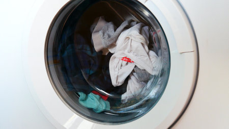 Close-up of a washing machine with the closed front door and clothes in itの写真素材