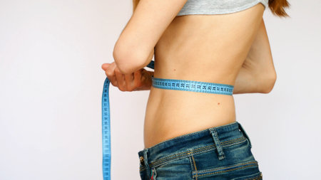 A young lady with a beautiful body measures her waistの写真素材