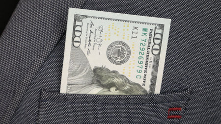 Close-up of one hundred dollar bill in somebody's blazer pocket