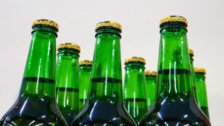 Close-up of many beautiful green glass bottles of beer with golden caps on a store shelfの写真素材