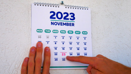 A beautiful November page of the wall calendar 2023 and a man points a finger at the marked Thanksgiving dateの写真素材