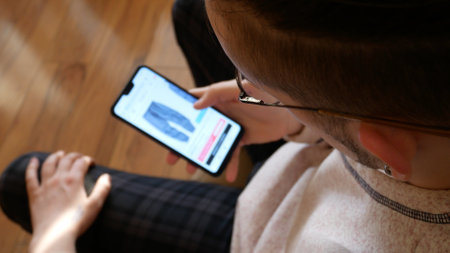 A young man choosing pants in an online store using a smartphone