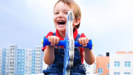 A happy laughing boy swinging on seesaw outdoorsの写真素材