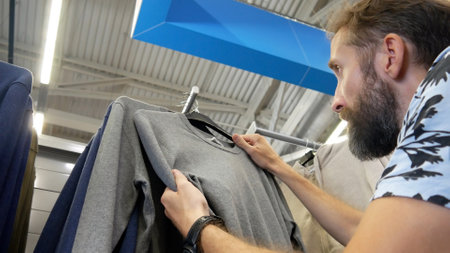 Close-up of a male buyer choosing a pullover in a clothing store