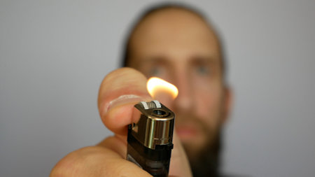 Close-up of a lighter fire in a man's outstretched handの写真素材