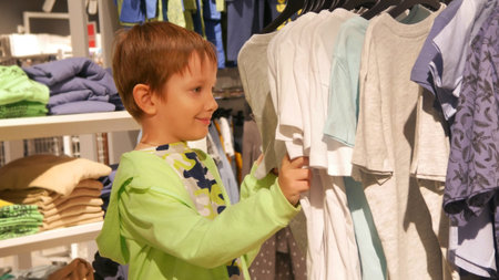 A cute boy chooses a t-shirt in a clothing store