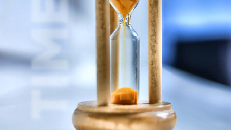 Close-up of a beautiful wooden hourglass with orange sand pouring insideの写真素材
