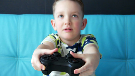 A cute boy playing video game console using a joystick