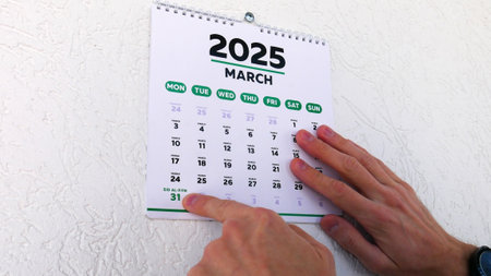 Close-up of a male hand pointing finger at Eid al-Fitr date 2025 on a wall calendarの写真素材