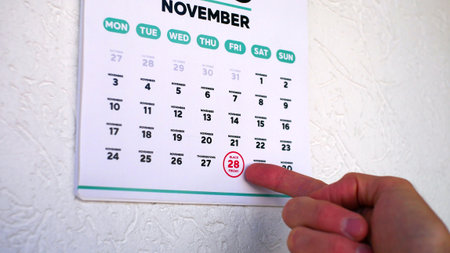 Close-up of a male hand pointing finger at Black Friday 2025 date on the page of a wall calendarの写真素材
