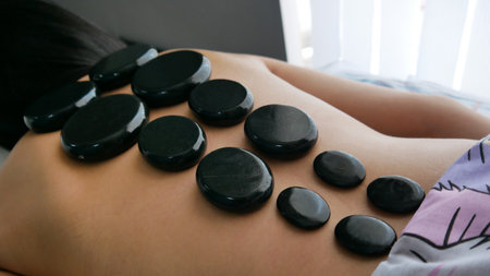 Close-up of many basalt massage stones warming a young woman's backの写真素材
