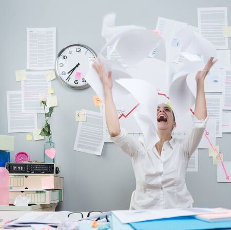 Angry businesswoman in office throwing paperwork in air and shouting.の写真素材