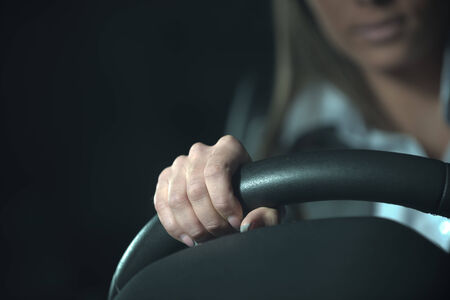 Woman driving a car late at night, hands on steering wheel close-up.の写真素材