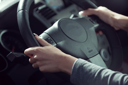Woman driving a car, hands on steering wheel close-up.の写真素材