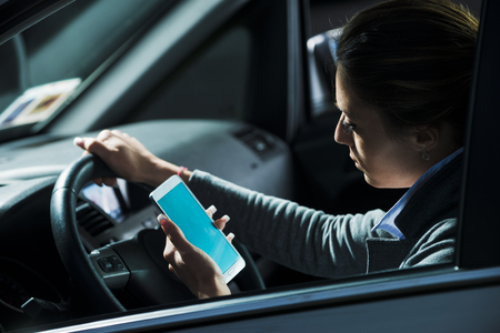 Young lost female driver using mobile phone while driving at night.