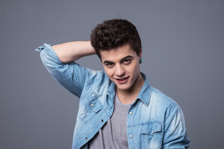 Shy smiling teenager boy with hand behing head