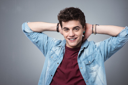 Smiling teenager relaxing with hands behind head and looking at camera