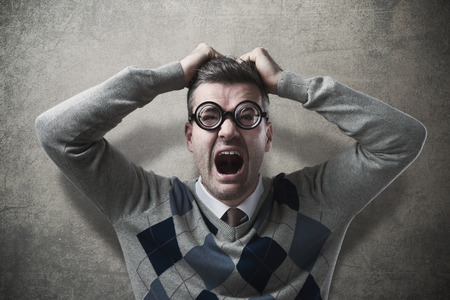 Desperate funny guy with head in hands screamingの写真素材